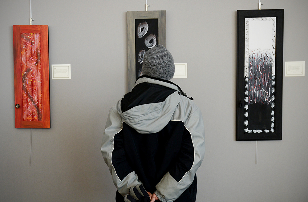 A passerby views Sarah Drake's "Open Doors" exhibit at the Great River Regional Library. Photo by Adam Hammer '05