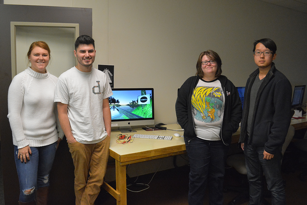 The four students stand in front of their project