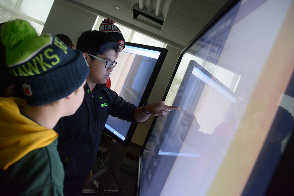 Students interact with a large touch screen
