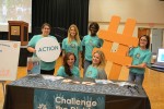 The six students stand at their booth holding up their giant hashtag symbol