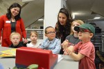 Preschool teachers and preschoolers stand before a toy cash registger