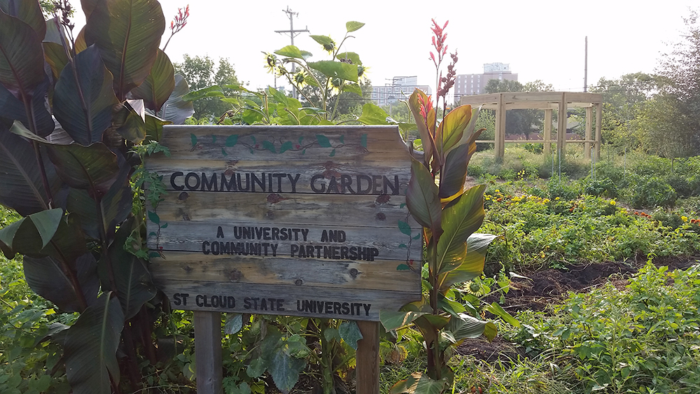 Community Garden sign with garden in the background