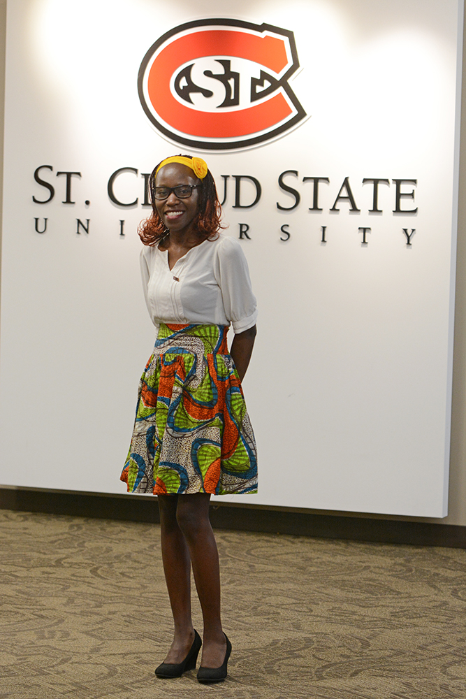 Lydia Mbatidde stands in front of a St. Cloud State sign