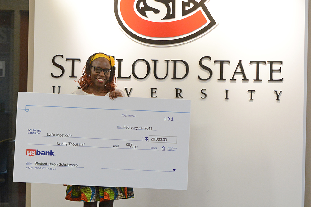 Lydia Mbatidde holding a big check