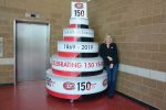 A woman stands next to a giant display cake