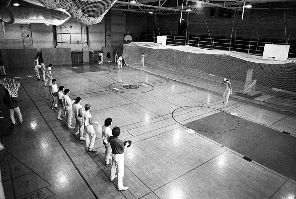 Baseball players line up to play catch on the gym floor