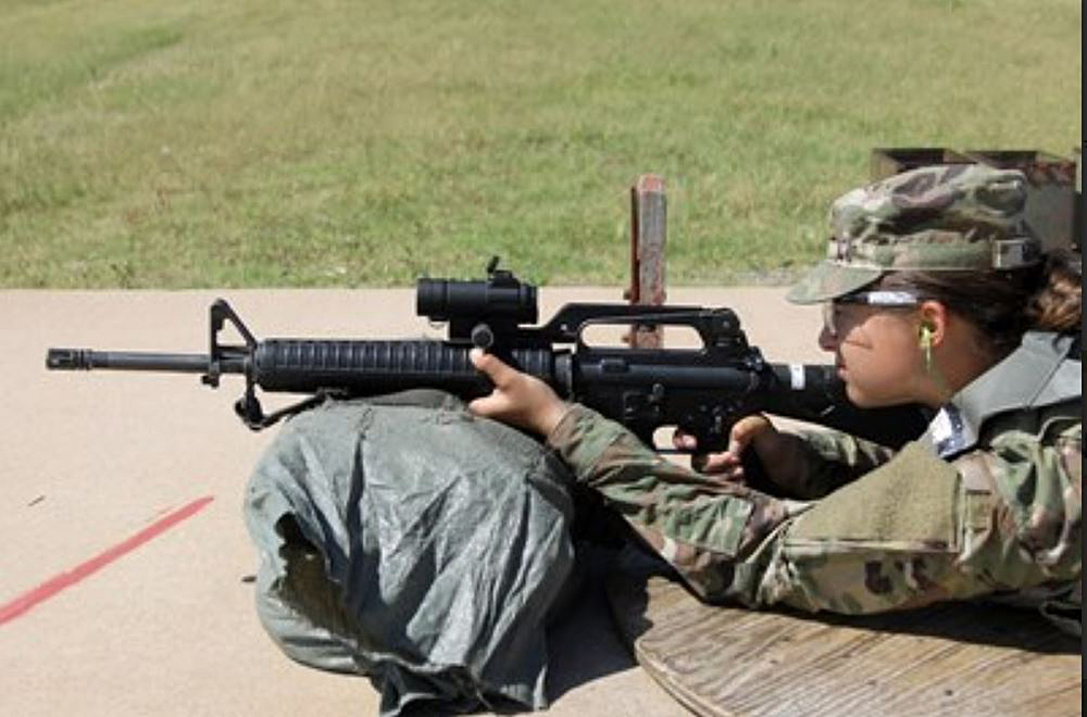 Woman shooting a gun in camouflage gear