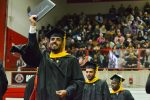 A man holds up his diploma during the ceremony