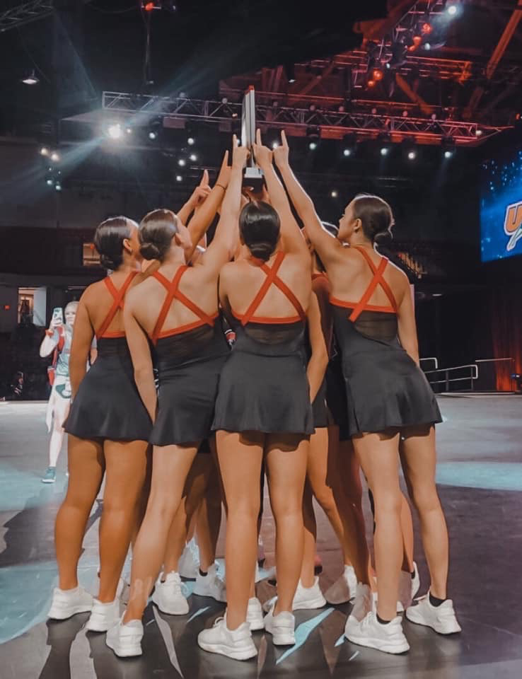 Dance team members hold up trophy on stage
