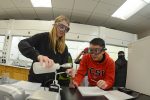Students wear goggles as they poor a liquid into a beaker