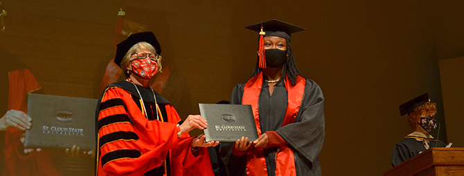 Dr. Wacker presenting St. Cloud State Student her diploma at Commencement ceremony