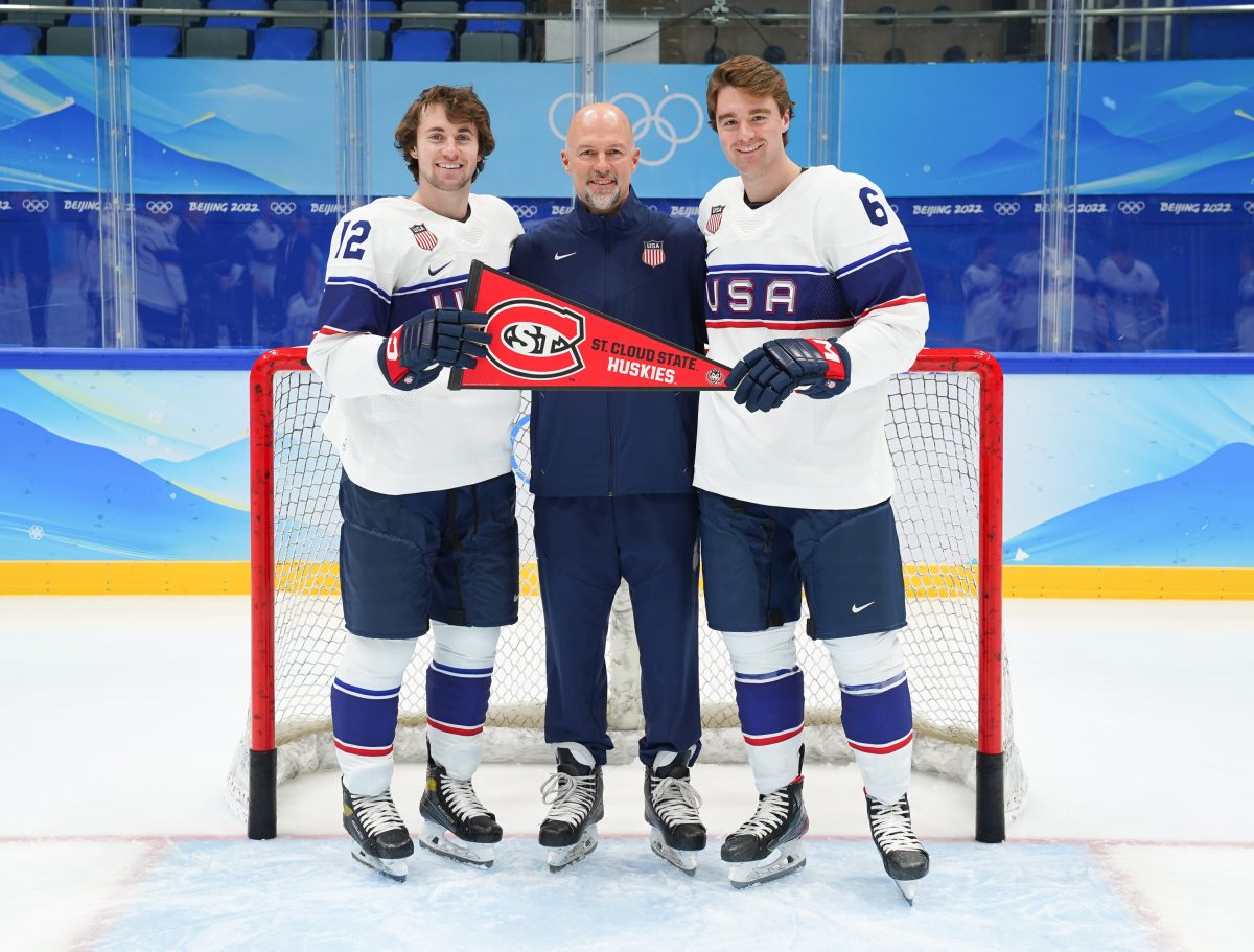 Brett Larson, Sam Hentges and Nick Perbix hold a St. Cloud State pennant on the Olympic ice. 
