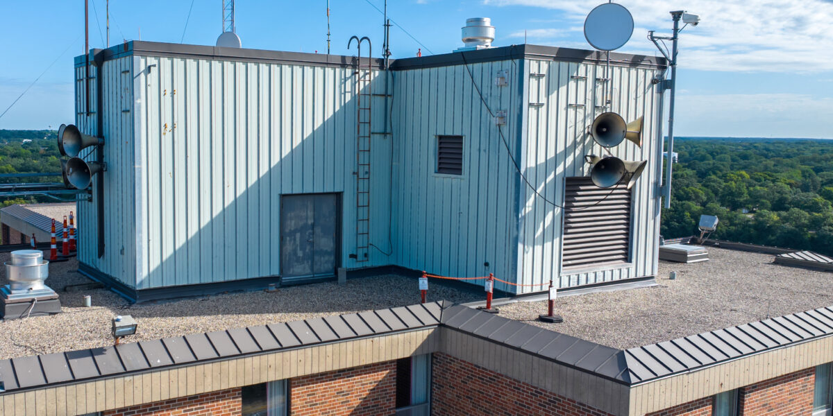 The roof of Sherburne Hall shows various speakers and cones on a sunny day