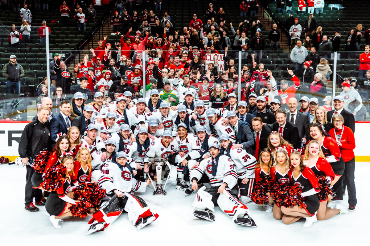 A large group of SCSU players and fans smile for a picture in the Xcel Energy Center