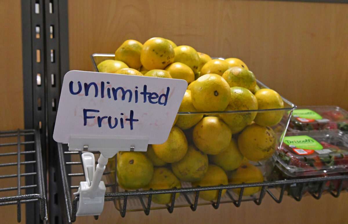 A large box of fruit and containers of strawberries are pictured next to a white sign that says unlimited fruit