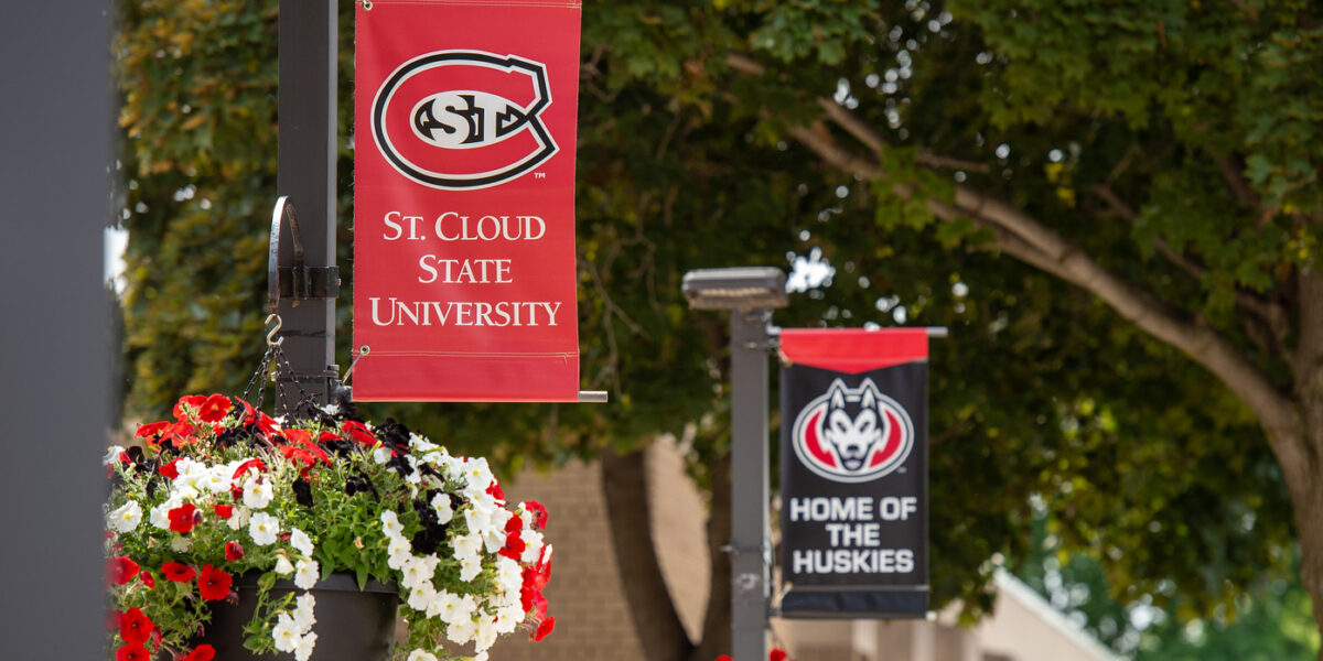 St. Cloud State University and Home of the Huskies banners are photographed next to flowers and trees