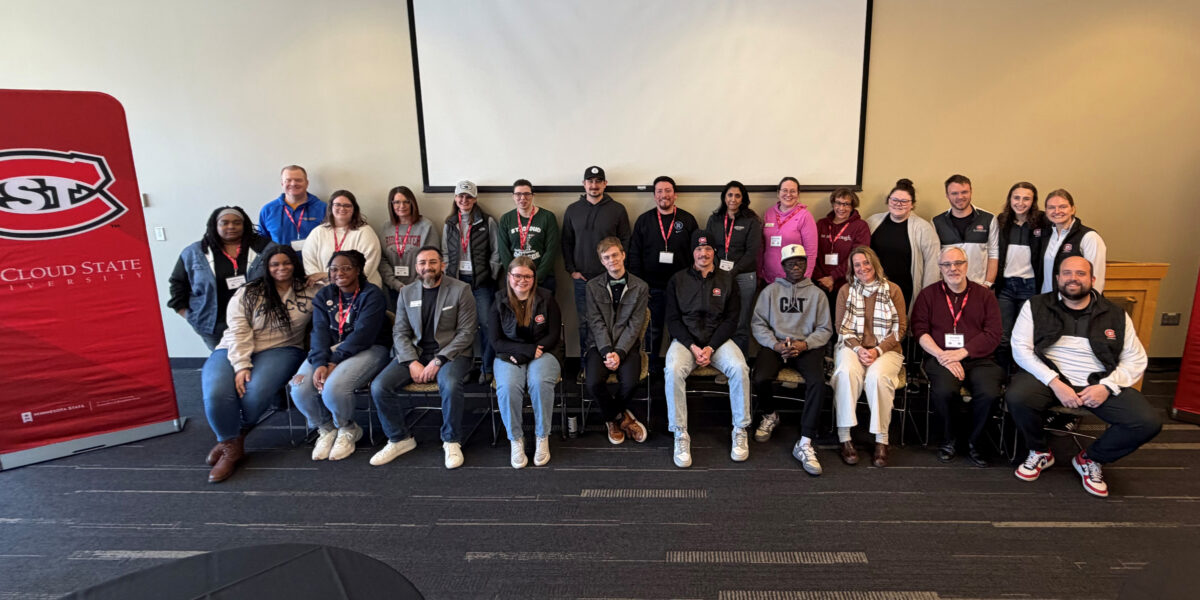 A group of 25 people are lined up in two rows for a group photo