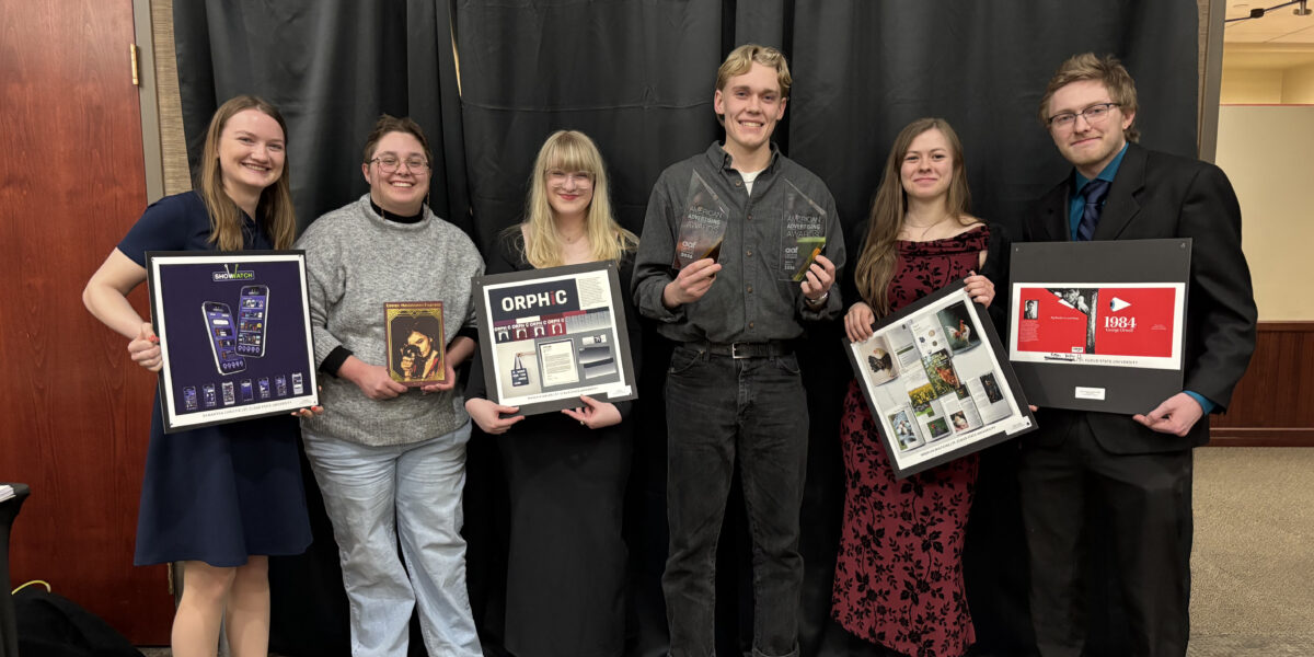 Six students smile for a photo while holding their graphic design projects or awards