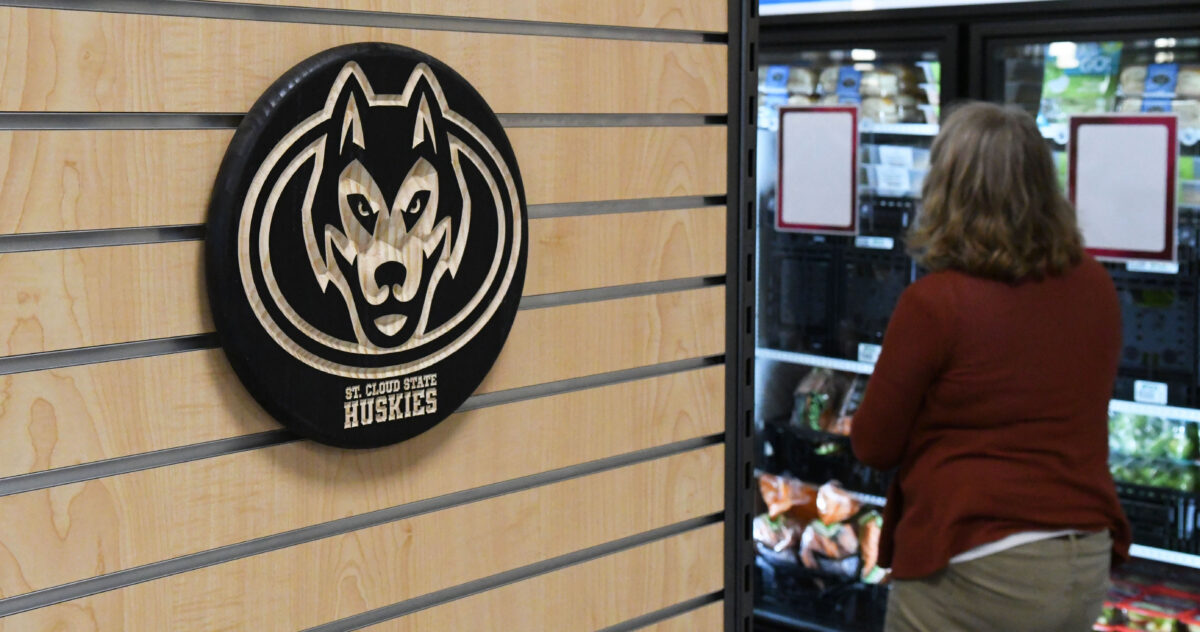 A black SCSU husky logo against wood is visible with a shopper and refrigerated items visible out of focus