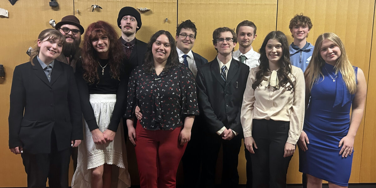 A group of 11 students in formal attire smile for a photo