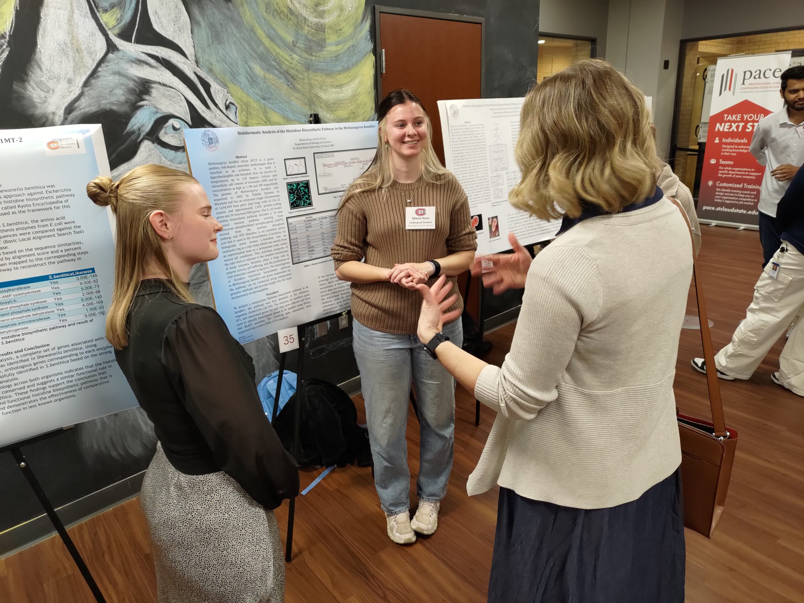 People talking in front of a poster board.