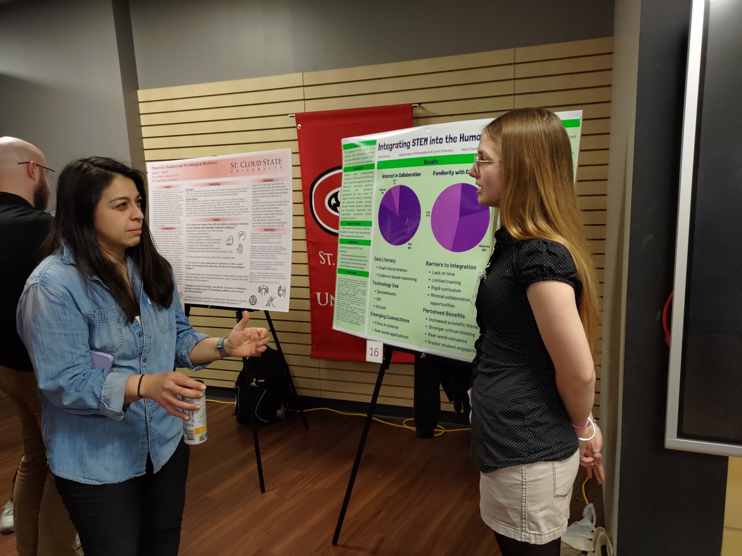 Two women talking in front of a poster board.