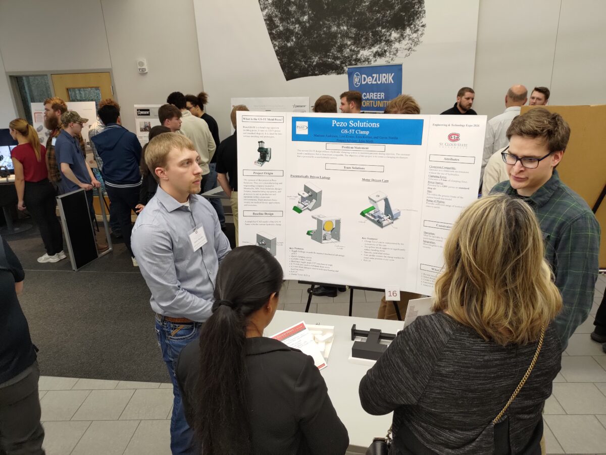 People gathered around a poster board and presenters.