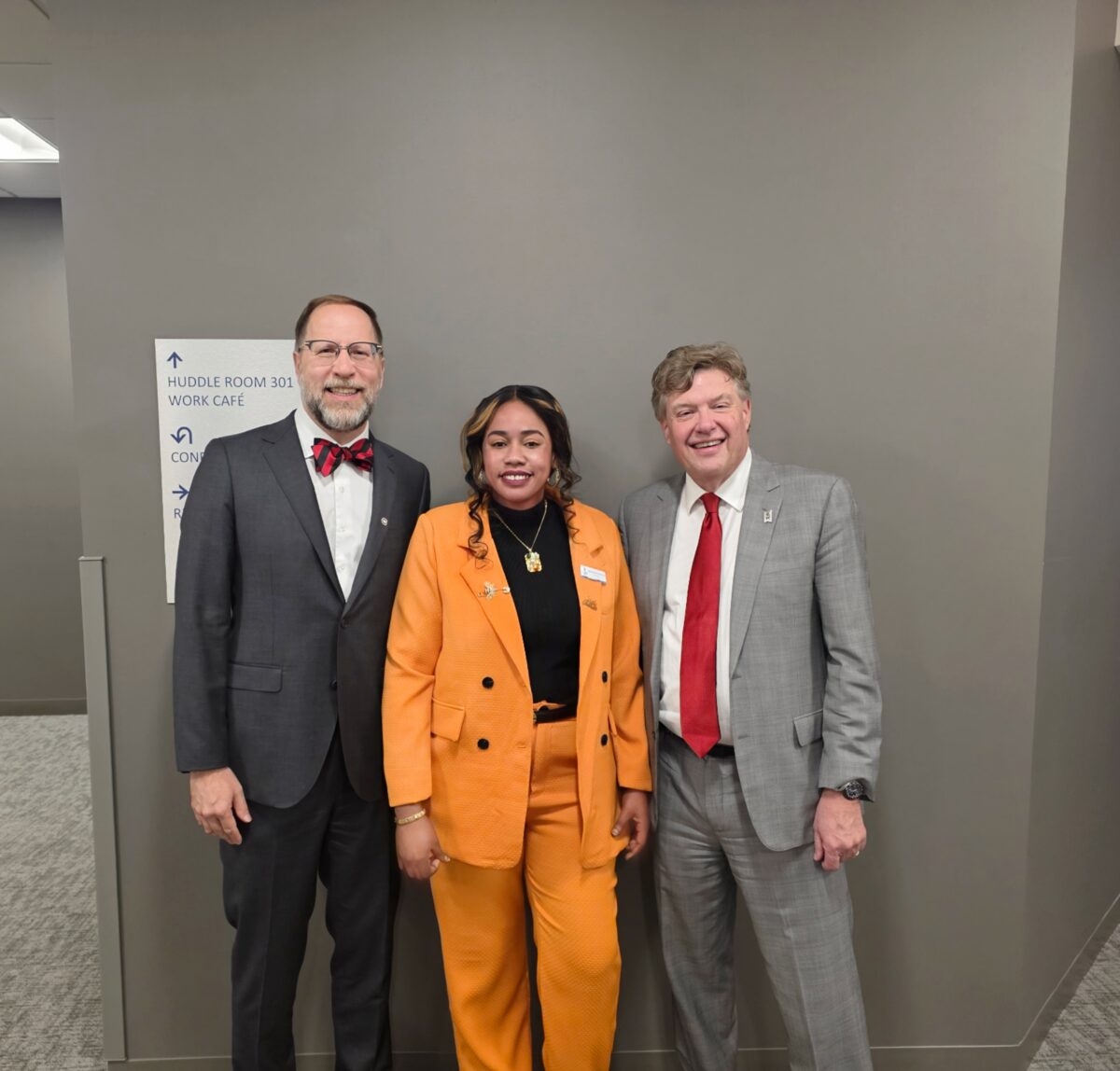 Three people smiling in professional attire.