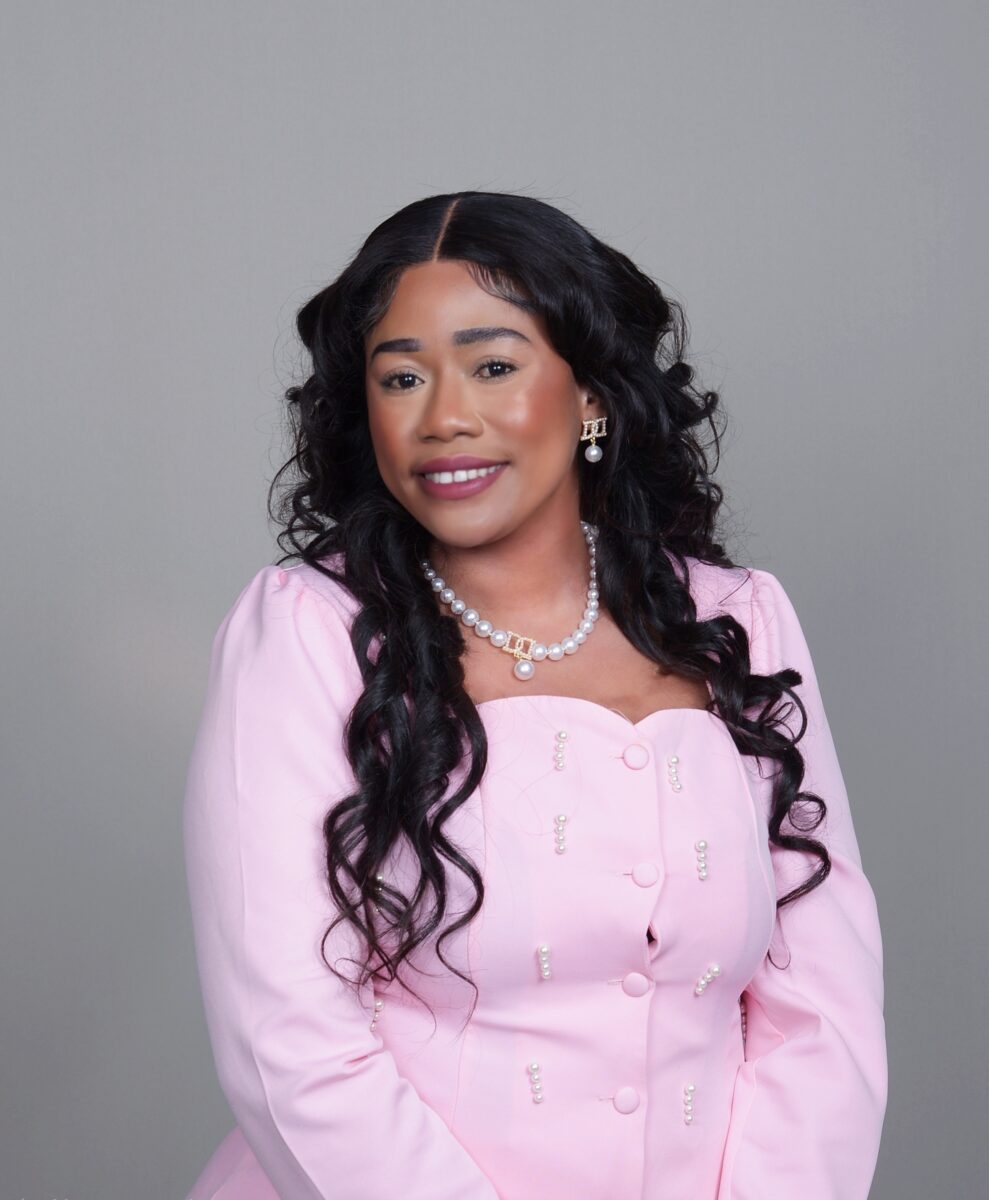 Woman smiles in pink blazer.