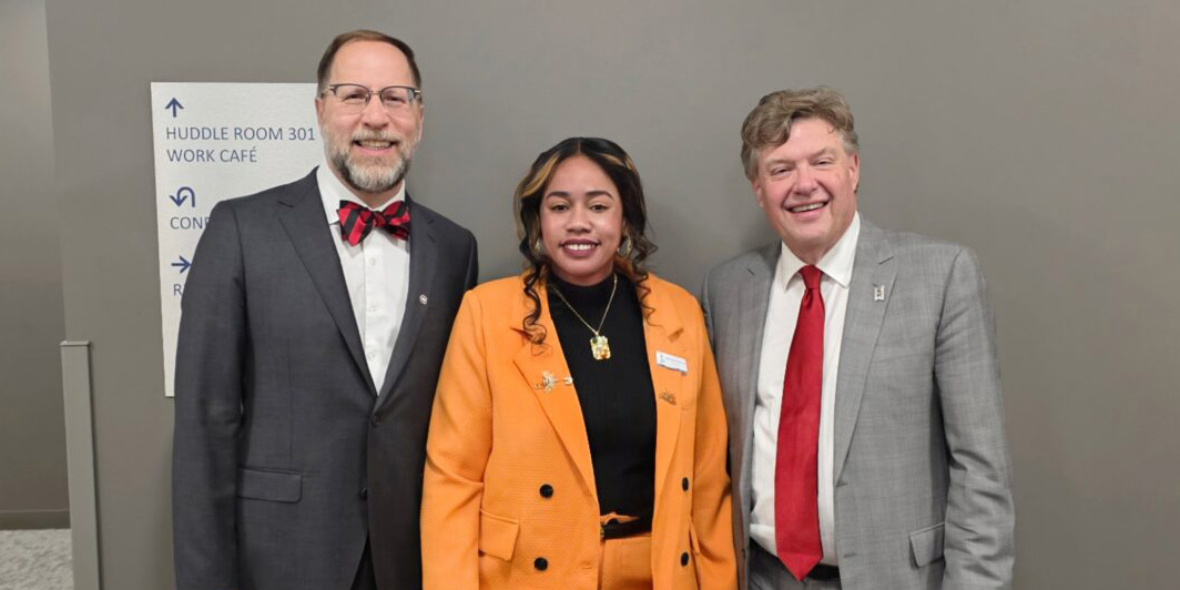 Three people smiling in professional attire.