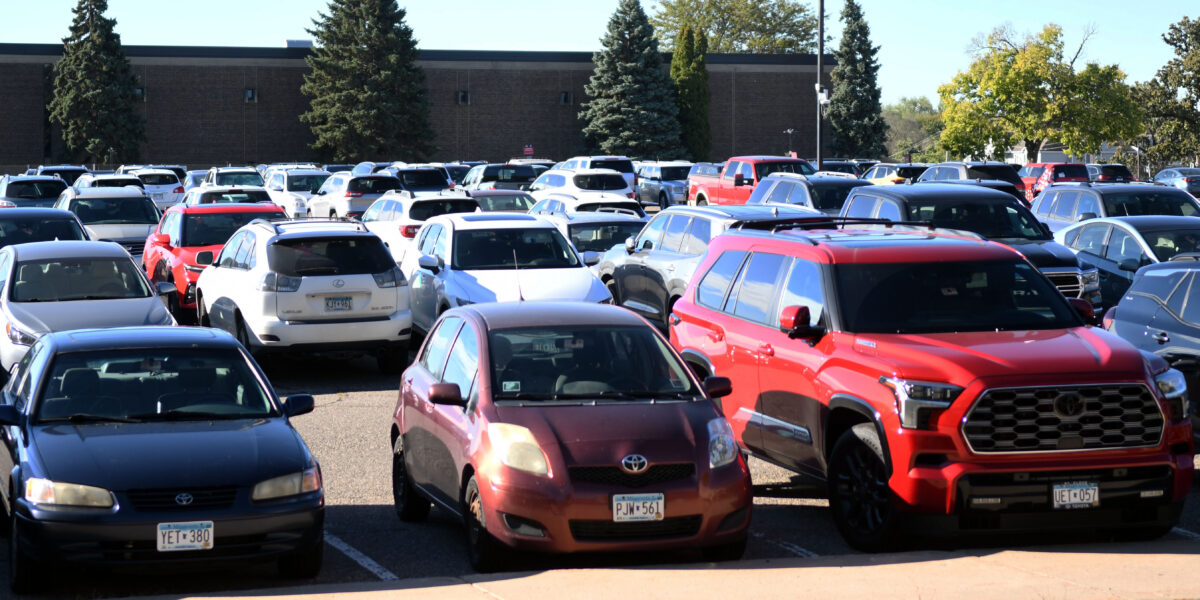 A parking lot full of cars is photographed near Halenbeck Hall