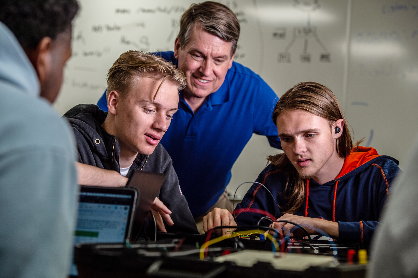 Students and a professor look at wiring in a computer science course