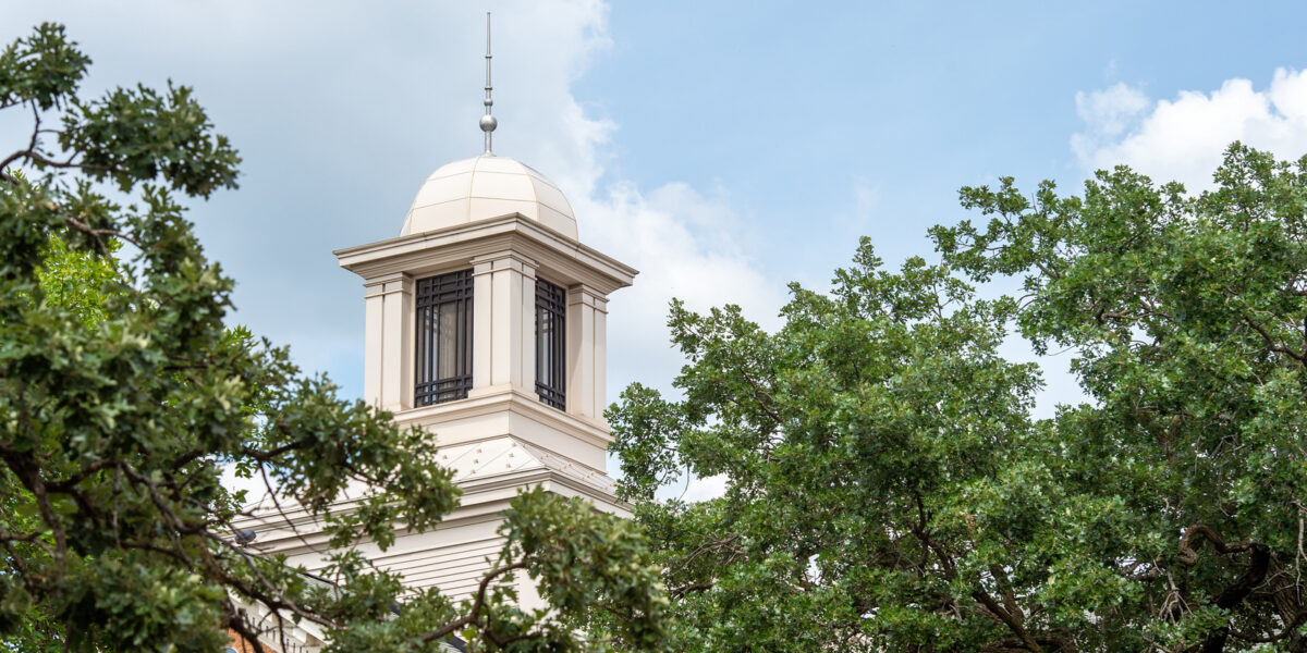 Lawrence Hall cupola is visible through the trees on a cloudy summer day