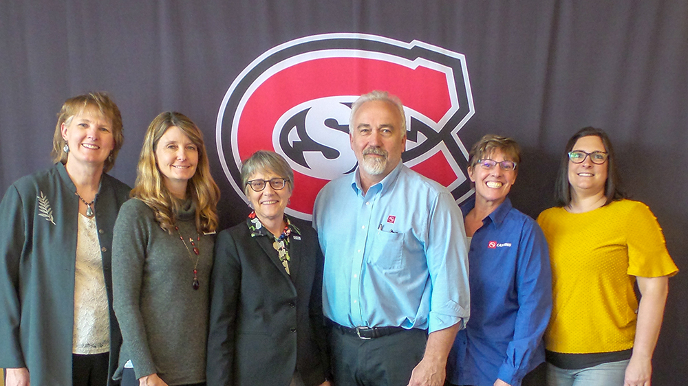 People standing in front of a St. Cloud State logo backdrop