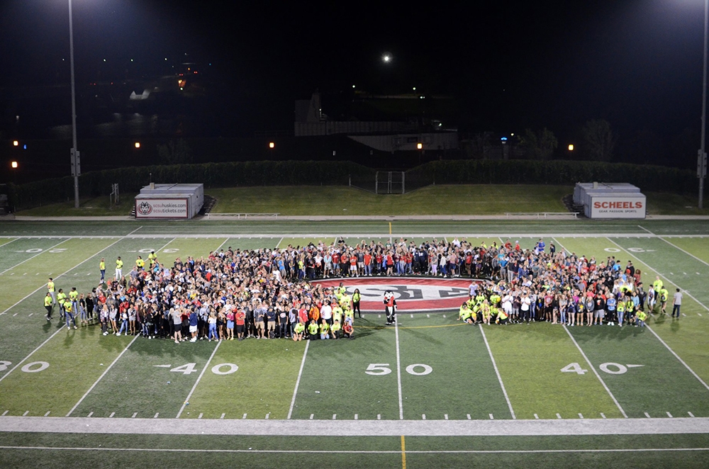 Lots of students huddled together on the football field