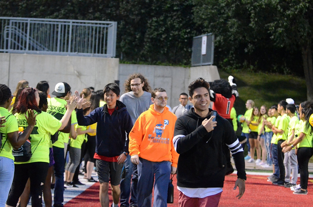 Students enter Husky Stadium through a line of Orientation Leaders