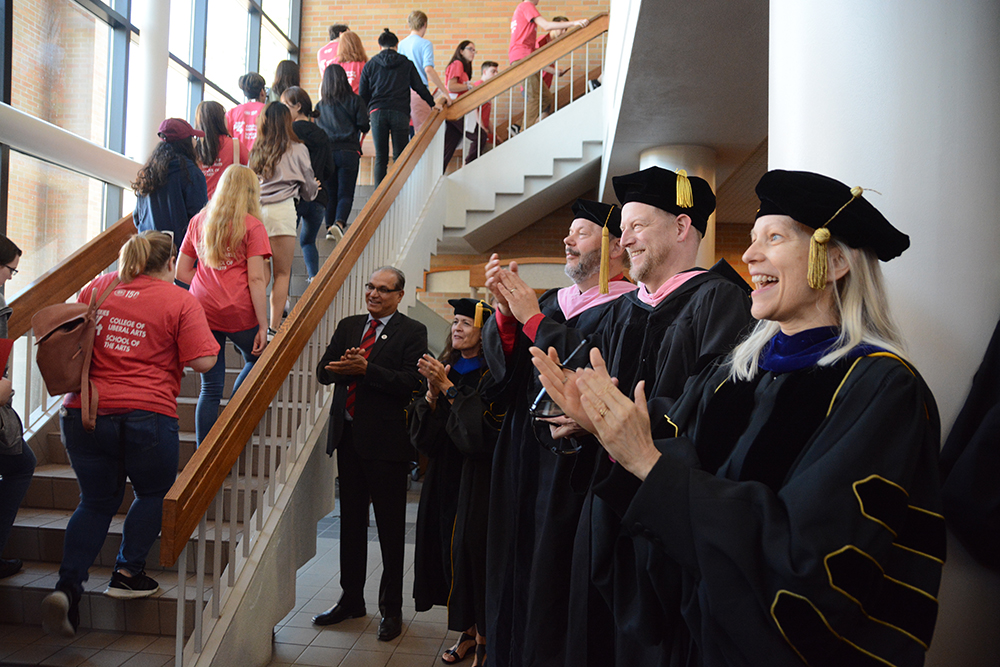 Faculty members clap as students go up the stairs