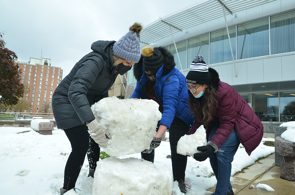 Three women building a snowman